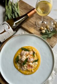 Tīģergarneles ar sviestā ceptas kukurūzas – saldā krējuma mērci, Makadāmijas riekstiem, ķirbju – ingvera biezeni un fritētu salviju.